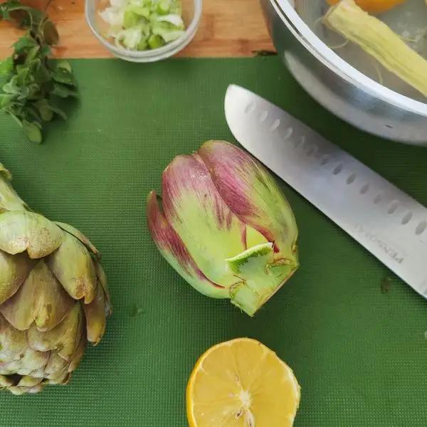 Immagine dello step: Come prima cosa si sgranano i legumi, ( o di utilizzano quelli surgelati scongelati) poi si tagliano i carciofi e si lasciano nell’acqua con il limone.