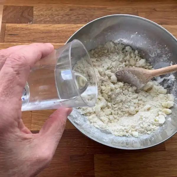 Immagine dello step: Dopo aver lessato le patate senza buccia a cubetti e passarli al setaccio in una ciotola, aggiungere l’amido di mais, la farina di riso e lo zucchero, mescolare con un cucchiaio di legno,