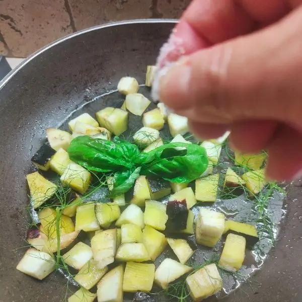 Immagine dello step: Tagliare la melanzana a cubetti e cuocerla in padella con aglio ed olio . Unire il basilico e salare .