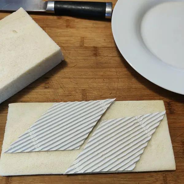 Immagine dello step: Intagliare da un cartoncino un rombo e ritagliare 28 rombi di pane in cassetta.