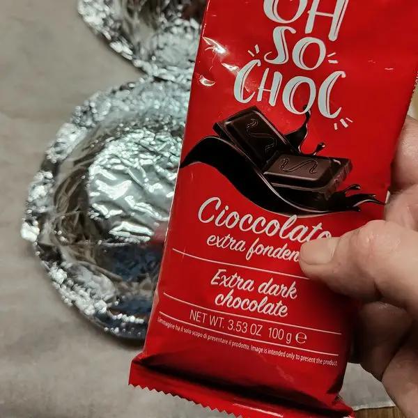 Immagine dello step: Fondere il cioccolato (in una pentola con acqua calda) tagliare l'angolo dell'incarto e spargere sulla coppa foderata con alluminio.