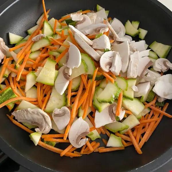 Immagine dello step: Preparare condimento mettendo in pentola zucchine e carote tagliate a julienne e funghi con un goccio d’olio e cipolla con coperchiò per 10/12min