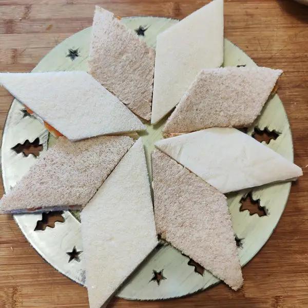 Immagine dello step: Spalmare il pane poi disporre i tramezzini a rombo, creando una stella con 8 rombi alla base e il  secondo strato con 6 rombi.