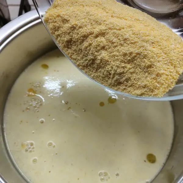 Immagine dello step: Cuocere la polenta  in acqua salata . Aggiungere olio qb, e al bollore versare la polenta girando. Dopo 8 minuti aggiungere del parmigiano e far amalgamare.