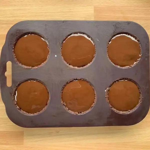 Immagine dello step: Riempire i gusci di cioccolato nelle formine di silicone, livellare con una spatolina e coprire con la glassa pinguino poi in congelatore per 1 ora