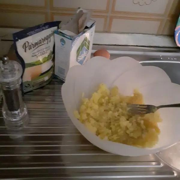 Immagine dello step: Prendete lo schiacciapatate e con una forchetta giratele aggiungete 1 uovo e girate e aggiungete formaggio grattugiato e sale e pepe.