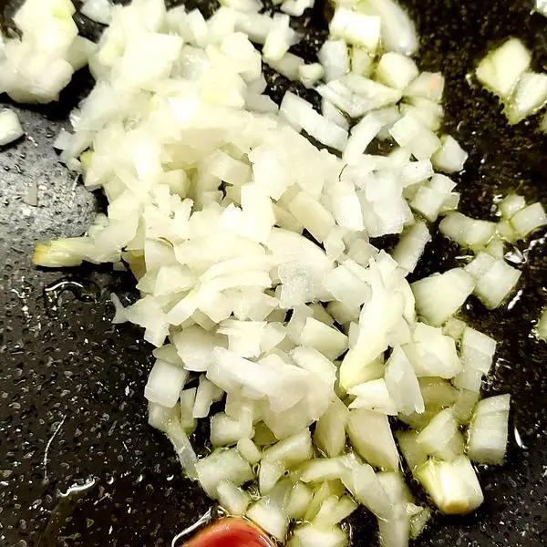 Immagine dello step: Rosolate uno spicchio di aglio in una padella con poco olio. Tagliate finemente la cipolla e unitela al soffritto.