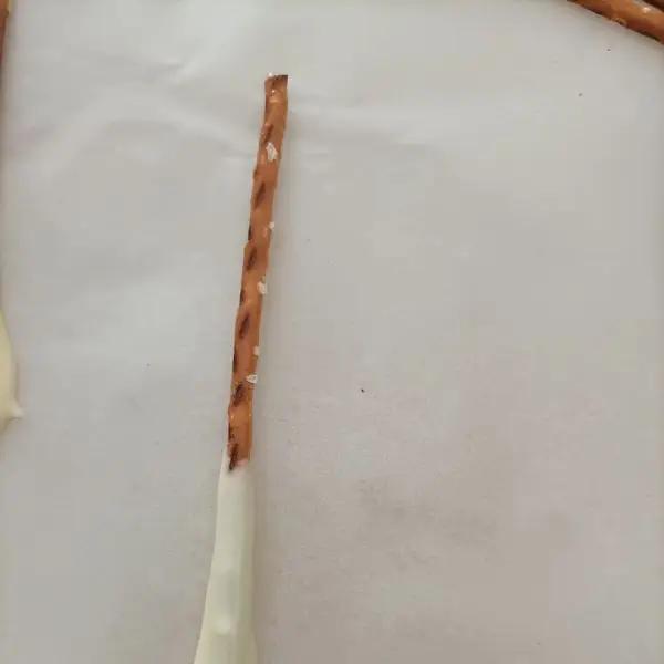 Immagine dello step: Inzuppare un bastoncino di Pretzel alla volta ,nel cioccolato bianco e posarlo su un vassoio con foglio di carta forno