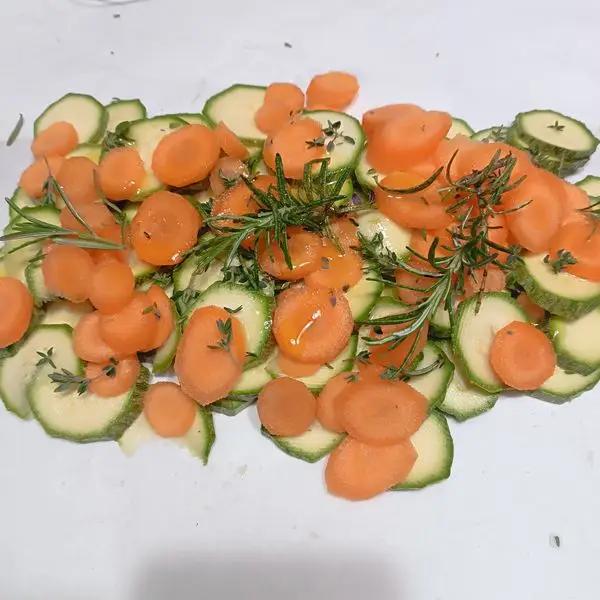 Immagine dello step: Spuntare le zucchine e carote, tagliarle a rondelle piuttosto sottili.Adagiarle sui fogli di carta forno,salare aggiungere le erbe aromatiche e un giro d'olio.