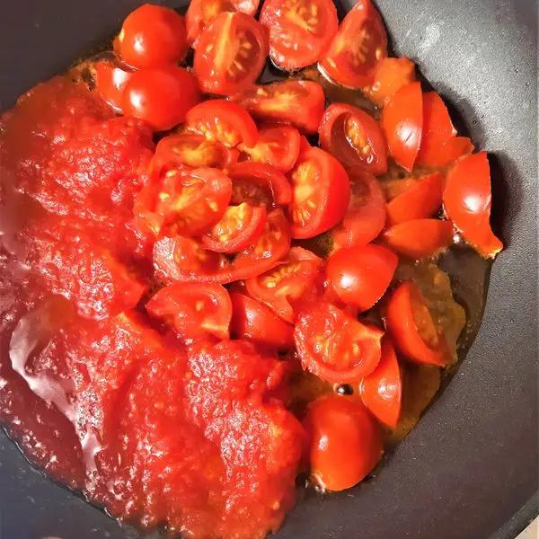 Immagine dello step: Fate soffriggere in una padella l'aglio con l'olio evo. Unite i pomodorini tagliati, il peperoncino e la salsa e fate cuocere a fiamma bassa per 10 minuti.